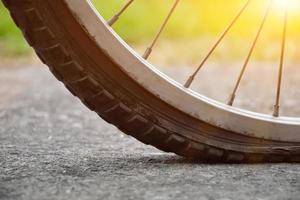 Close up view of bike which has flat tire and parked on the pavement, blurred background. Soft and selective focus on tire. photo