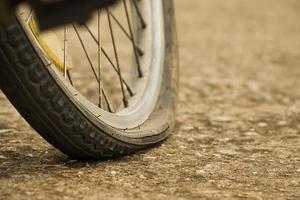 Close up view of bike which has flat tire and parked on the pavement, blurred background. Soft and selective focus on tire. photo