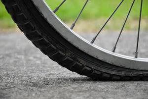 Close up view of bike which has flat tire and parked on the pavement, blurred background. Soft and selective focus on tire. photo