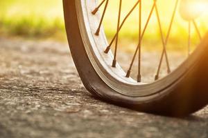 Close up view of bike which has flat tire and parked on the pavement, blurred background. Soft and selective focus on tire. photo