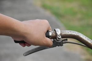 A young guy holds handle bars of vintage bike which parked on the meadow background, soft and selective focus on hand. photo