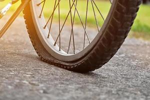 vista de cerca de la bicicleta que tiene un neumático desinflado y estacionado en el pavimento, fondo borroso. enfoque suave y selectivo en el neumático. foto
