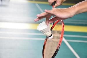 Badminton player holds racket and white cream shuttlecock in front of the net before serving it to another side of the court. photo