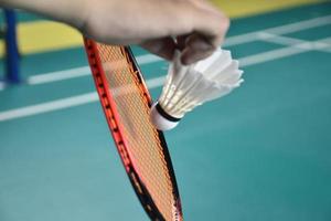 Badminton player holds racket and white cream shuttlecock in front of the net before serving it to another side of the court. photo