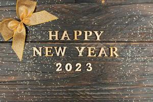 A symbol from the number 2023 with golden sequins and bow on a wooden background. The concept of celebrating a Happy New Year and Christmas. photo