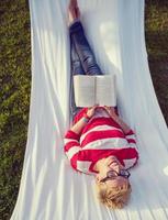 woman reading a book while relaxing on hammock photo