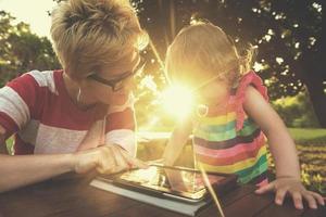 mom and her little daughter using tablet computer photo