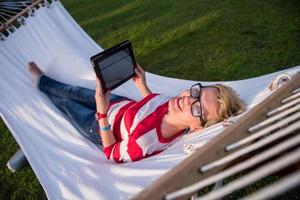 woman using a tablet computer while relaxing on hammock photo