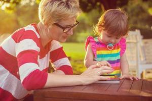 mom and her little daughter using tablet computer photo