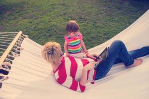 mamá y una pequeña hija relajándose en una hamaca foto