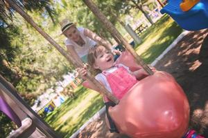 mother and daughter swinging in the park photo