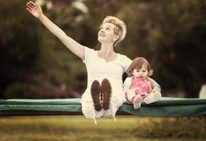 mother and little daughter swinging at backyard photo