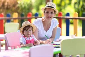 mamá y su pequeña hija dibujando imágenes coloridas foto