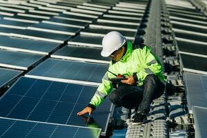 el retrato de un joven ingeniero comprueba los paneles solares fotovoltaicos. concepto. servicio de electricidad de tecnología de energía renovable, energía verde. foto