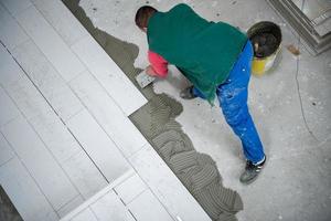 trabajador instalando las baldosas cerámicas con efecto madera en el suelo foto