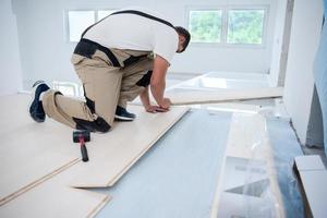 Worker Installing New Laminated Wooden Floor photo