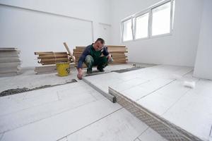 worker installing the ceramic wood effect tiles on the floor photo