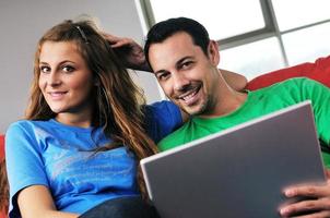 una pareja feliz se divierte y trabaja en una laptop en casa foto