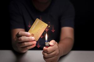 man hand holding credit card and he is burning credit card Concept of the financial impact of using credit cards. photo