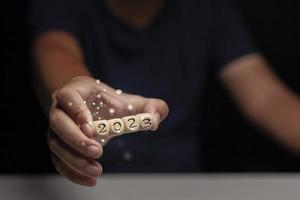 Man's hand holding a wooden dice with numbers 2023, concept of stepping into 2023. photo