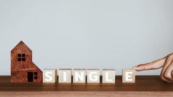 Man's hand scrolling the letter e to combine with the rest of the words to get the word single on wooden cubes block. photo