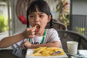 joven asiática comiendo papas fritas niño divertido papa feliz comida rápida. foto