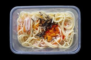 Top view of Spaghetti Creamy Crab Stick and Tobiko in plastic box for delivery at home isolated on black background included clipping path. photo