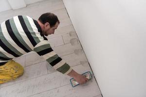 Tilers filling the space between ceramic wood effect tiles photo