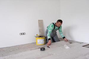 worker installing the ceramic wood effect tiles on the floor photo