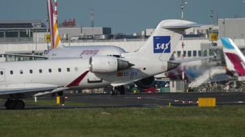 dusseldorf, Duitsland juli 21, 2017 - lucht nostrum bombardier crj 900 ec jzv in sas Scandinavisch luchtvaartmaatschappijen kleurstelling taxiën naar de begin Bij zonsondergang. dusseldorf luchthaven video