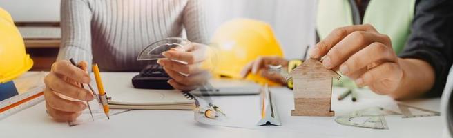 Two colleagues discussing data working and tablet, laptop with on on architectural project at construction site at desk in office photo