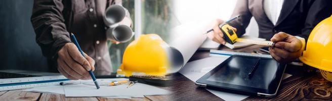 Two colleagues discussing data working and tablet, laptop with on on architectural project at construction site at desk in office photo