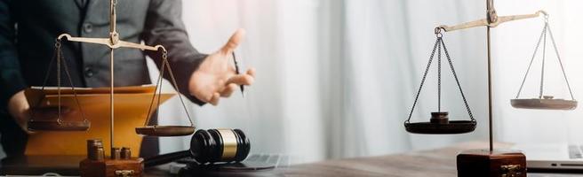 Business and lawyers discussing contract papers with brass scale on desk in office. Law, legal services, advice, justice and law concept picture with film grain effect photo