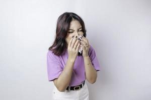 Portrait of sad upset young Asian woman in scarf blows her nose and wipes nose with tissue. Health problems, fever, illness, cold, flu and covid-19 virus, copy space photo