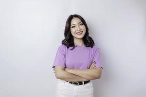 retrato de una mujer asiática sonriente confiada de pie con los brazos cruzados y mirando la cámara aislada sobre fondo blanco foto