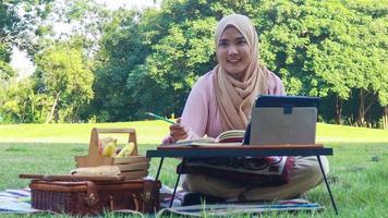 Muslim woman working with tablet in park beautiful muslim girl working online video