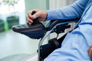 Asian elderly woman disability patient sitting on electric wheelchair in park, medical concept. photo