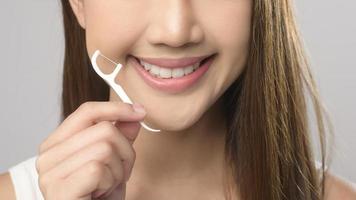 joven mujer sonriente sosteniendo hilo dental sobre estudio de fondo blanco, cuidado de la salud dental y concepto de ortodoncia. foto