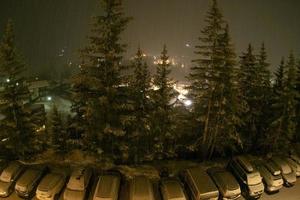 snowing at night in dolomites mountains car park photo