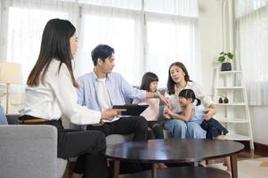 Asian family meeting with female real estate agent or insurance consultant offering promotions , Mortgage, loan, property and medical health insurance concept. photo