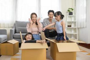 Asian family husband and wife and children with cardboard boxes having fun on moving day, Mortgage, loan, property and insurance concept. photo