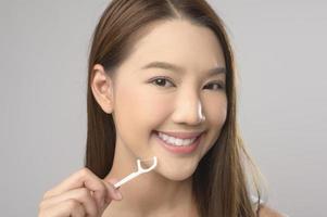 Young smiling woman holding dental floss over white background studio, dental healthcare and Orthodontic concept. photo