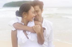 Happy young couple wearing white dress on the beach on holidays, travel, romantic, wedding concept photo