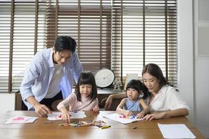 Asian family with children Drawing and painting on table in playing room at home, Educational game. photo