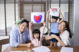 familia asiática con niños dibujando y pintando en la mesa en la sala de juegos en casa, juego educativo. foto