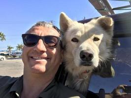 man with white wolf dog while looking at you photo