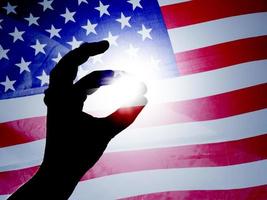 hand catching the sun on american flag photo