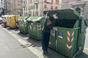 Génova, Italia - 9 de junio de 2017 - migrante buscando comida dentro del contenedor de basura foto