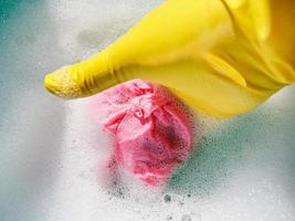 hand in yellow rubber glove wrings out wet cloth photo