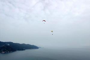 paraglider on cloudy sky in monterosso cinque terre italy photo